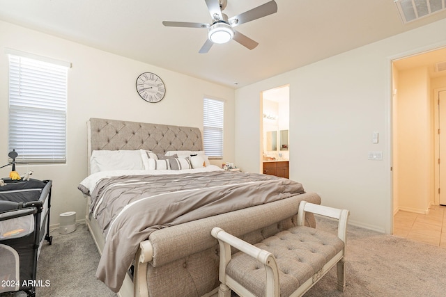 carpeted bedroom with ensuite bath and ceiling fan