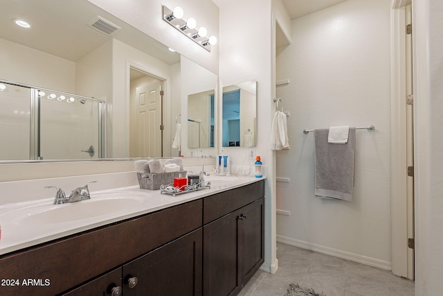 bathroom with a shower with door, vanity, and tile patterned flooring