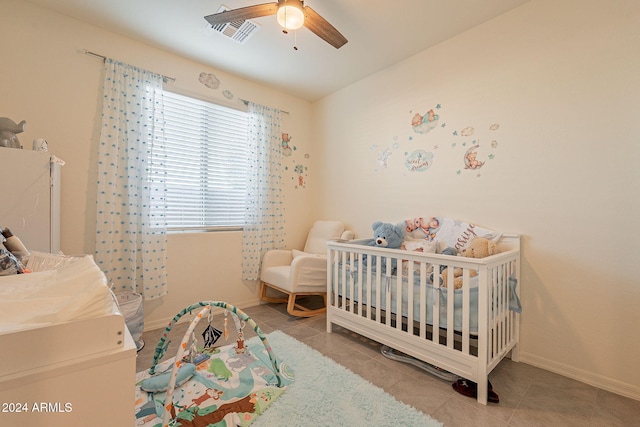 bedroom featuring ceiling fan, a crib, and light tile patterned floors