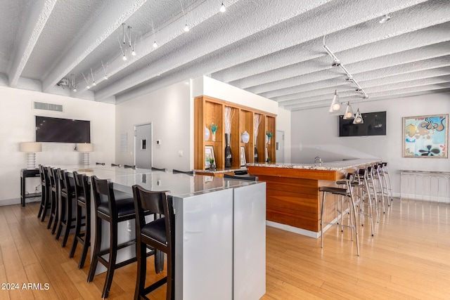 kitchen with light wood-type flooring, a kitchen breakfast bar, light stone counters, and kitchen peninsula