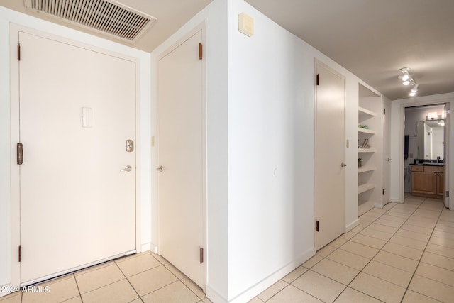 hallway with light tile patterned flooring and rail lighting