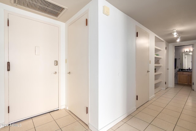 hallway featuring light tile patterned floors and built in features