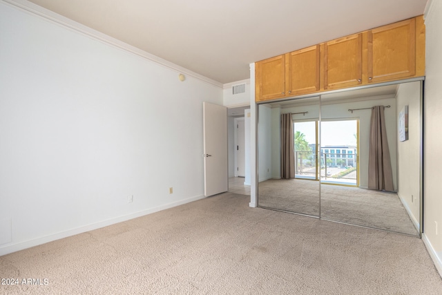 unfurnished bedroom featuring a closet, crown molding, and light colored carpet