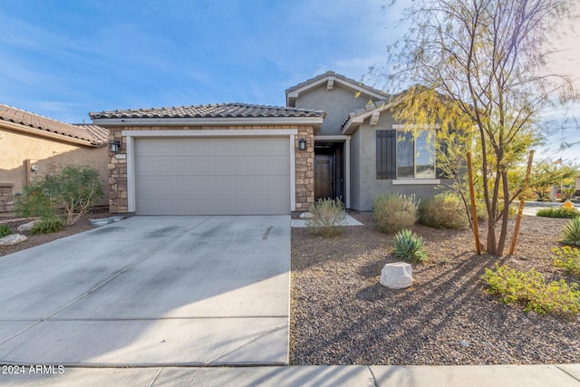 ranch-style home featuring a tile roof, stucco siding, an attached garage, stone siding, and driveway