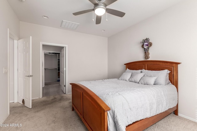 bedroom with baseboards, light colored carpet, ceiling fan, a walk in closet, and a closet