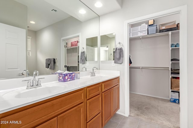 bathroom featuring double vanity, a spacious closet, visible vents, and a sink