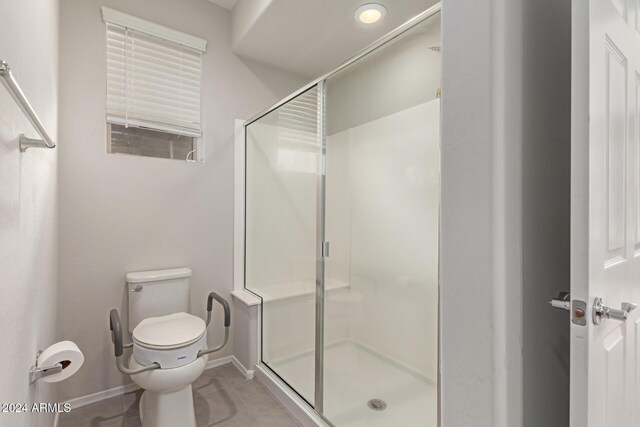 bathroom featuring a stall shower, toilet, baseboards, and tile patterned floors