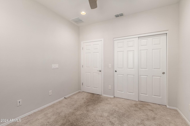 unfurnished bedroom with a closet, visible vents, light carpet, and baseboards