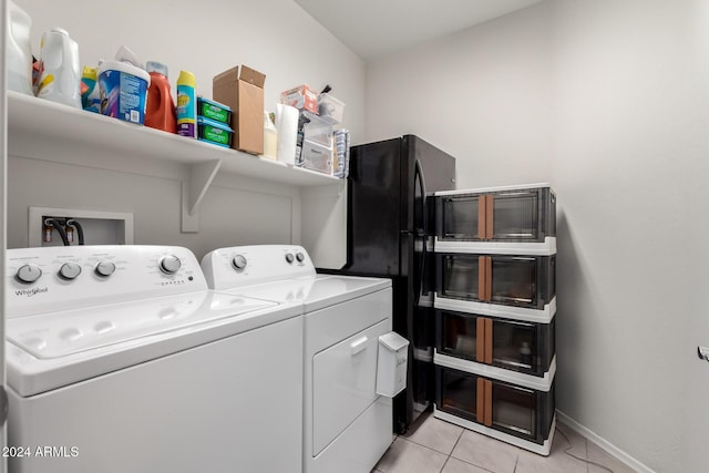 clothes washing area featuring laundry area, light tile patterned floors, baseboards, and washer and clothes dryer