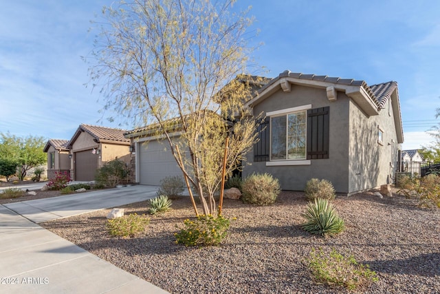 view of front of house featuring a garage, concrete driveway, a tiled roof, and stucco siding