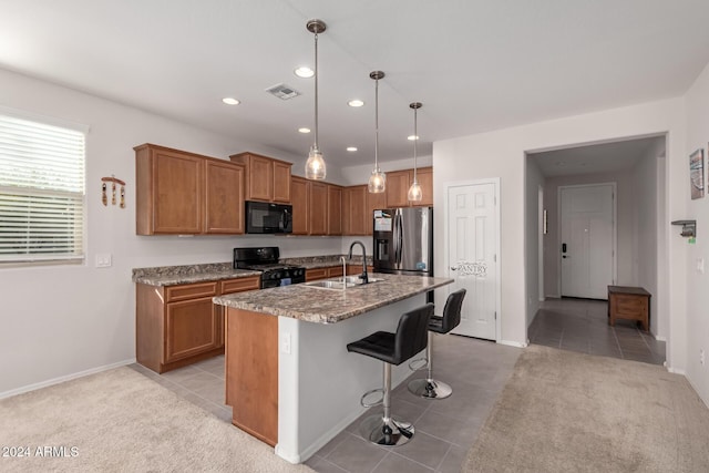 kitchen with a kitchen island with sink, a breakfast bar, a sink, visible vents, and black appliances