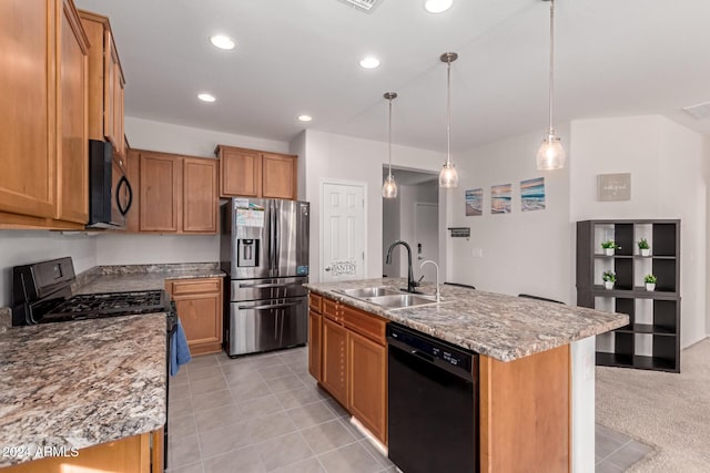 kitchen with a sink, an island with sink, black appliances, and light stone countertops