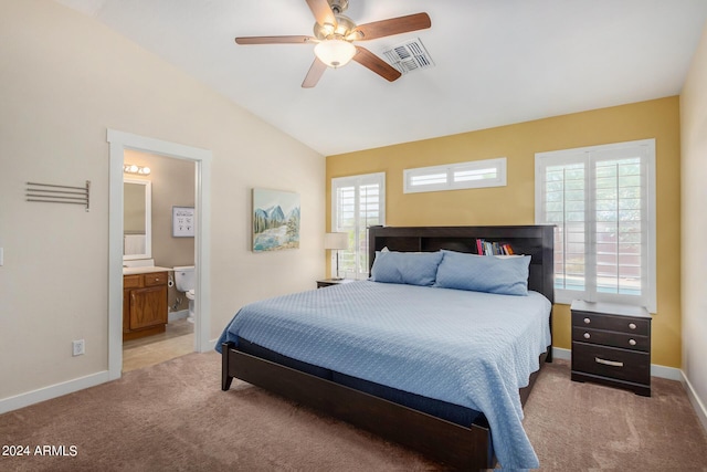 bedroom with lofted ceiling, connected bathroom, light colored carpet, and ceiling fan