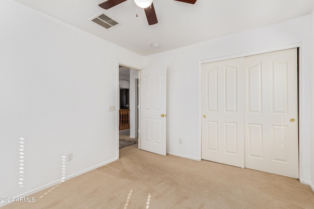 unfurnished bedroom featuring light carpet, a closet, and ceiling fan