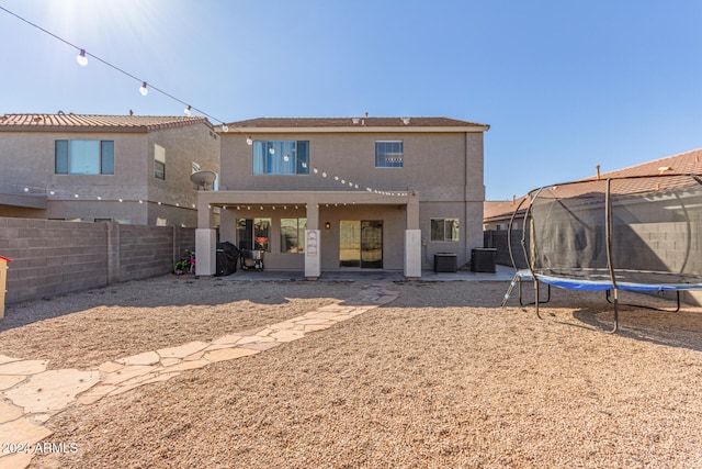 rear view of property with a trampoline, a patio, and central AC