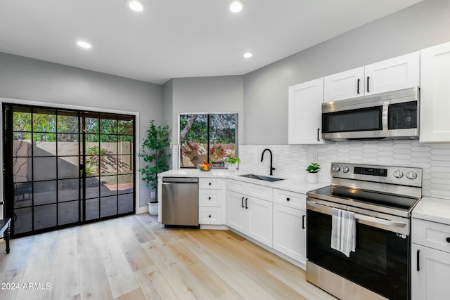 kitchen with white cabinets, appliances with stainless steel finishes, light hardwood / wood-style floors, and sink