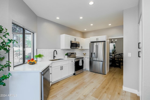 kitchen with white cabinets, sink, light hardwood / wood-style flooring, appliances with stainless steel finishes, and light stone counters