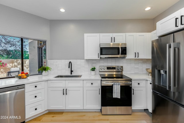 kitchen with white cabinets, light stone counters, sink, and stainless steel appliances