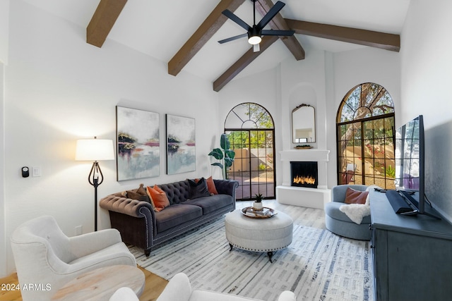 living room with ceiling fan, beamed ceiling, high vaulted ceiling, hardwood / wood-style floors, and a fireplace