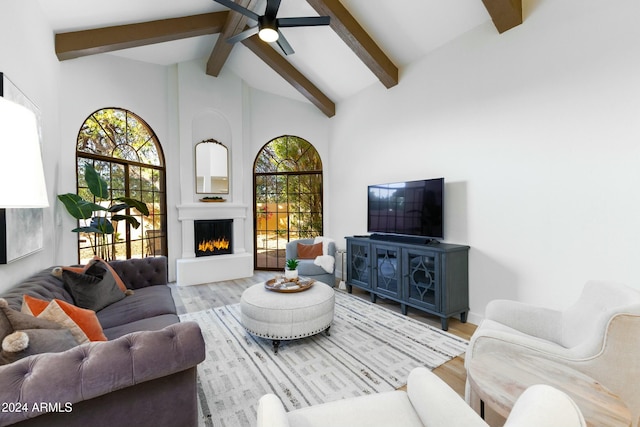 living room with ceiling fan, a large fireplace, high vaulted ceiling, beamed ceiling, and hardwood / wood-style flooring