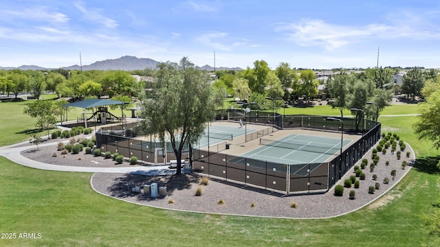view of tennis court featuring fence, a yard, and a mountain view