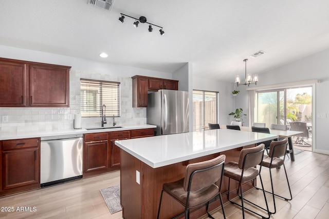 kitchen featuring vaulted ceiling, pendant lighting, sink, a center island, and stainless steel appliances