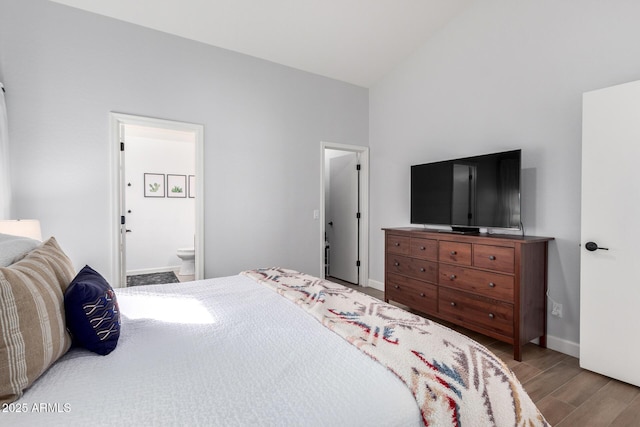 bedroom featuring lofted ceiling, hardwood / wood-style floors, and connected bathroom