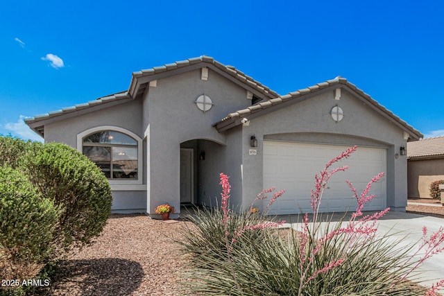 mediterranean / spanish-style house with an attached garage, stucco siding, driveway, and a tiled roof