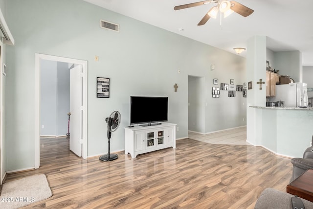 living room with ceiling fan, light wood-style flooring, and baseboards