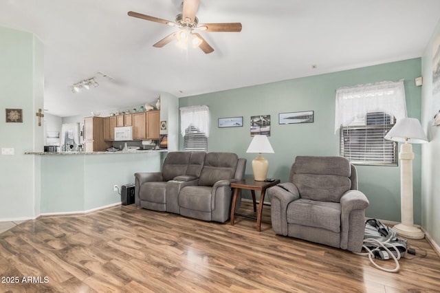 living area featuring wood finished floors, ceiling fan, baseboards, and track lighting