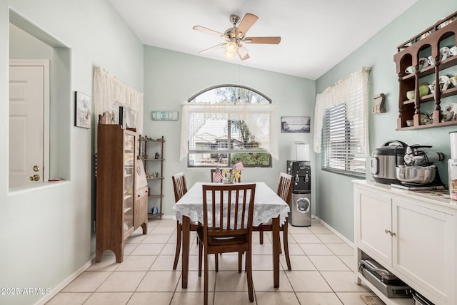dining space with a ceiling fan, lofted ceiling, light tile patterned flooring, and baseboards