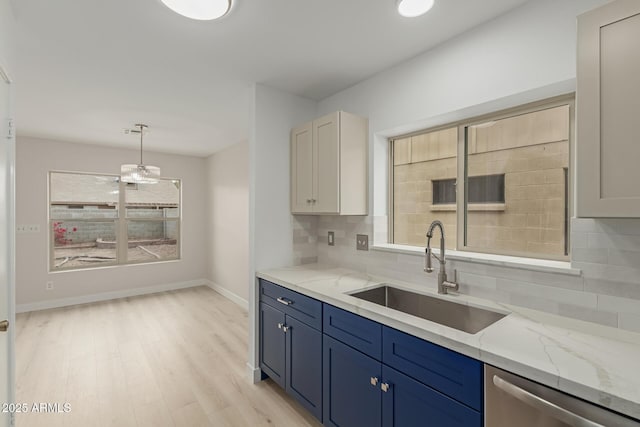 kitchen with dishwasher, light stone counters, blue cabinetry, and a sink