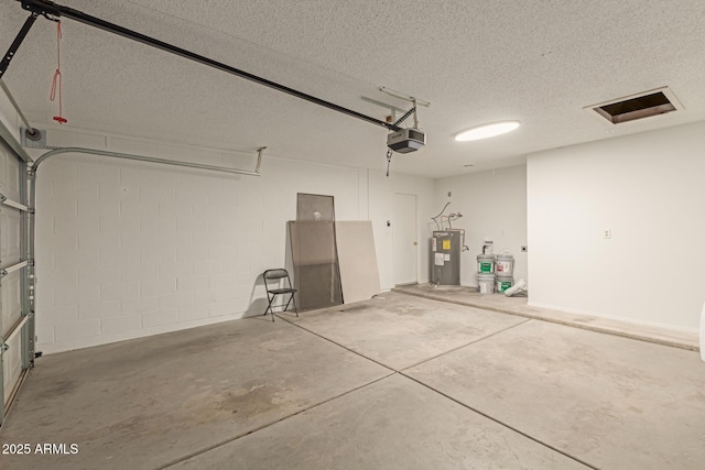 garage featuring a garage door opener, concrete block wall, and water heater