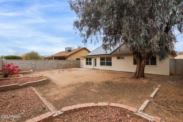 back of property with a fenced backyard and central AC