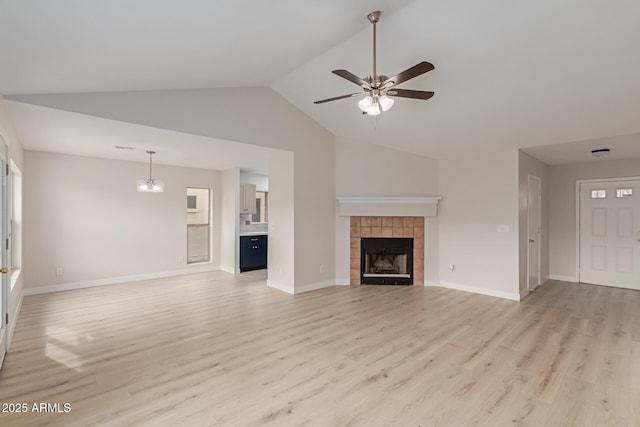 unfurnished living room with baseboards, light wood-style flooring, a tiled fireplace, and ceiling fan with notable chandelier