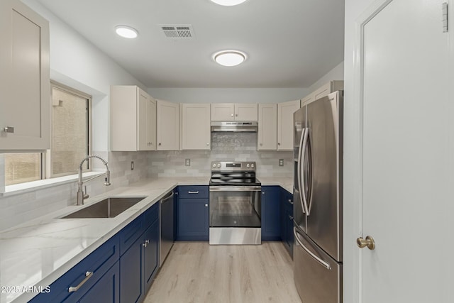 kitchen featuring decorative backsplash, appliances with stainless steel finishes, blue cabinets, under cabinet range hood, and a sink