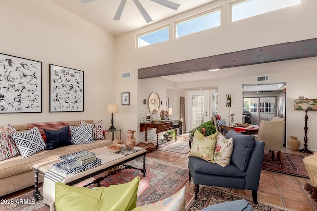 living room with tile patterned floors, ceiling fan, and a towering ceiling