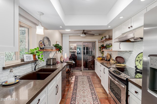 kitchen featuring appliances with stainless steel finishes, sink, decorative light fixtures, dark stone countertops, and white cabinets