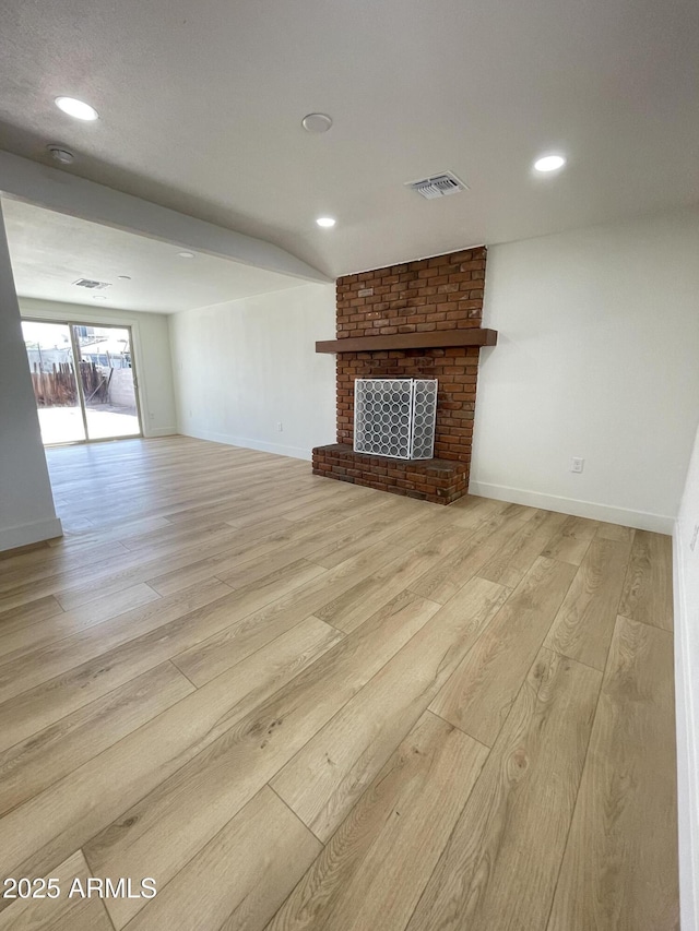 unfurnished living room featuring light wood-style floors, a brick fireplace, visible vents, and baseboards