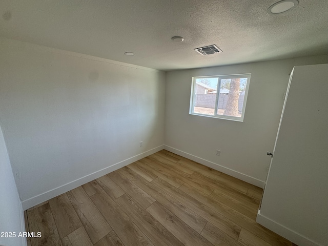 spare room featuring visible vents, light wood-style flooring, and baseboards