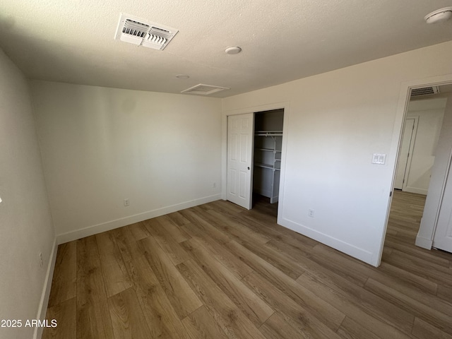 unfurnished bedroom featuring baseboards, visible vents, and wood finished floors