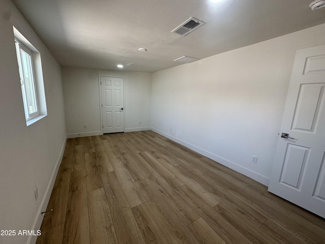 unfurnished room with baseboards, visible vents, and wood finished floors