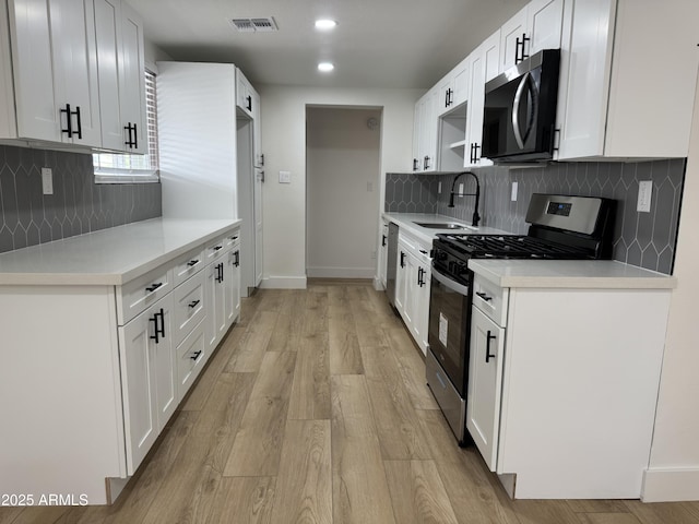 kitchen featuring a sink, visible vents, light countertops, appliances with stainless steel finishes, and light wood finished floors