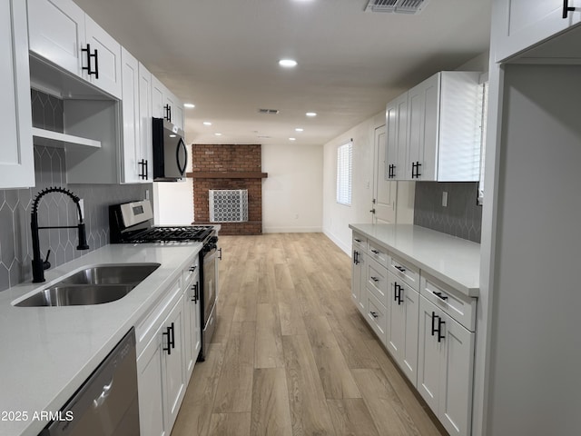 kitchen with light wood finished floors, visible vents, decorative backsplash, stainless steel appliances, and a sink