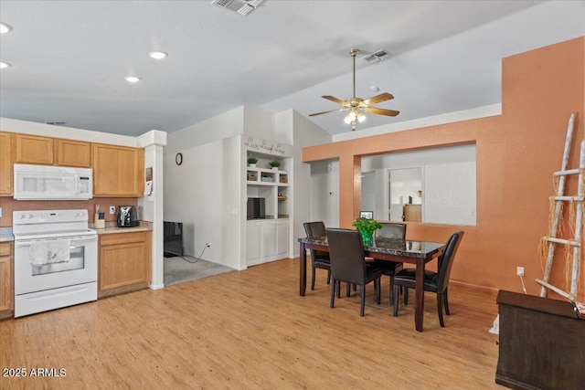 dining room featuring a ceiling fan, light wood-type flooring, visible vents, and lofted ceiling