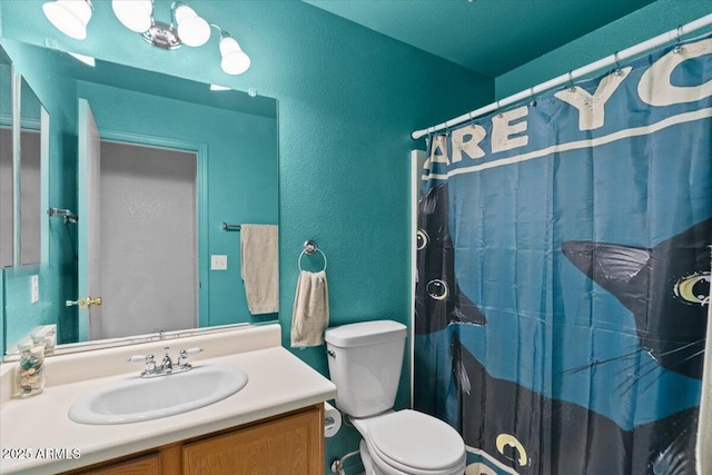 full bathroom featuring a textured wall, toilet, vanity, and a shower with curtain