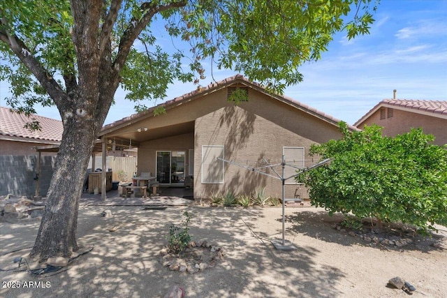 back of house featuring fence, a patio, stucco siding, and a tiled roof