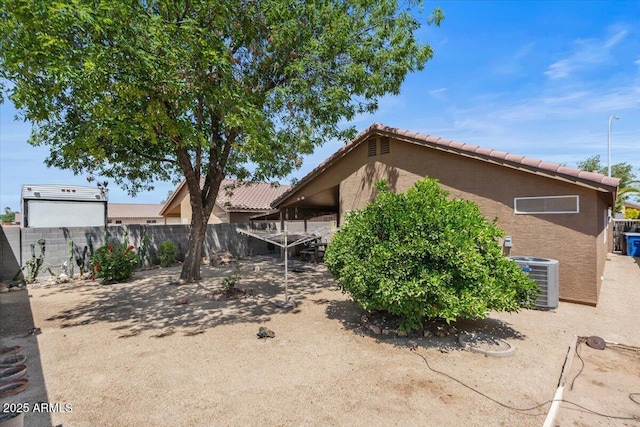 exterior space featuring a tiled roof, central AC unit, stucco siding, and fence