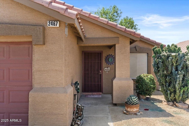 doorway to property featuring stucco siding and a tiled roof