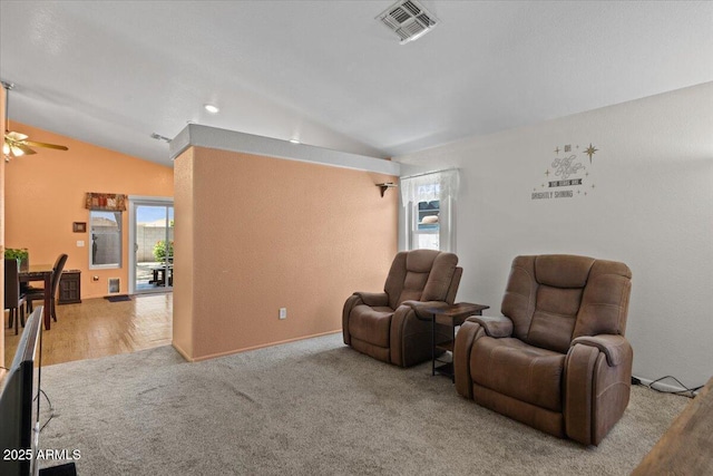 sitting room with lofted ceiling, ceiling fan, visible vents, and carpet